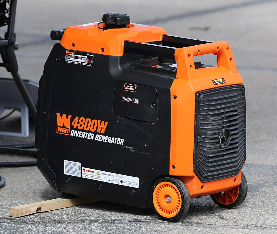An orange and black WEN 4800 inverter generator with wheels, sitting on pavement, for storm prep in Hiawatha, IA
